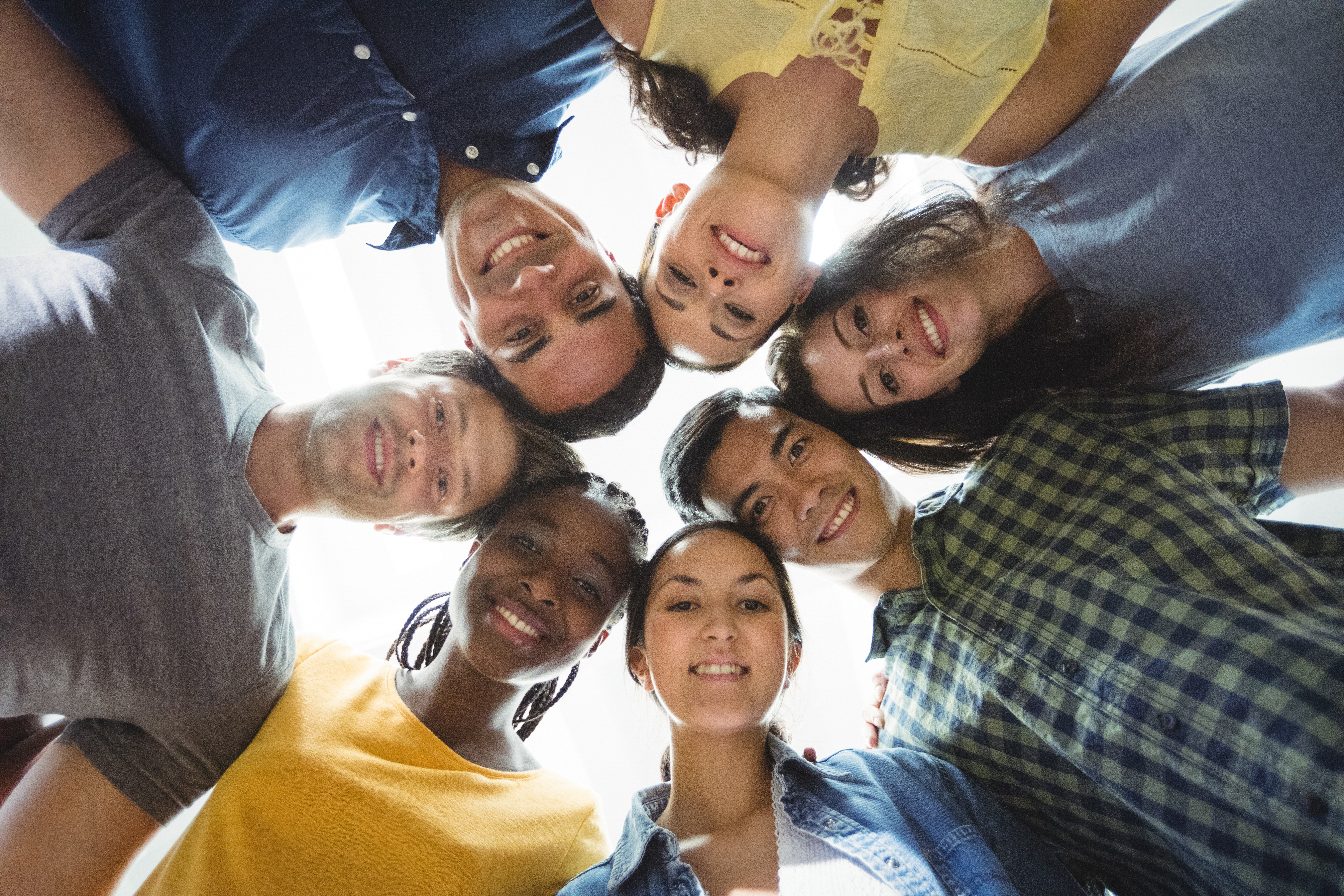Group of happy business executives forming huddle in office